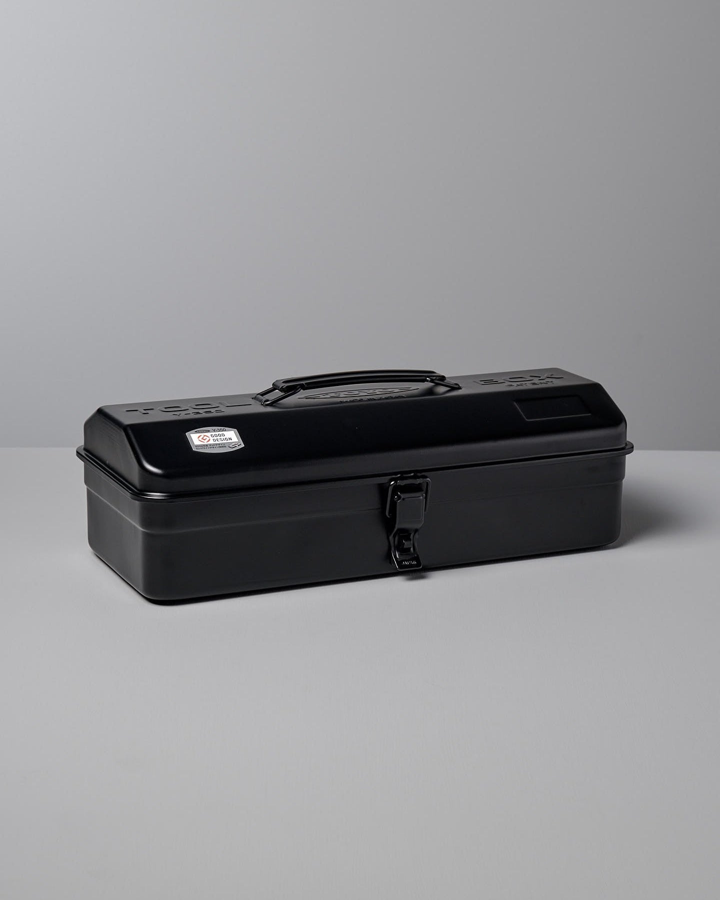 A closed black, camber-top toolbox made from powder-coated steel, featuring a handle on the lid and a latch on the front. This sleek design earned the Camber-Top Toolbox Y-350 – Black by TOYO STEEL the Good Design Award 2009.