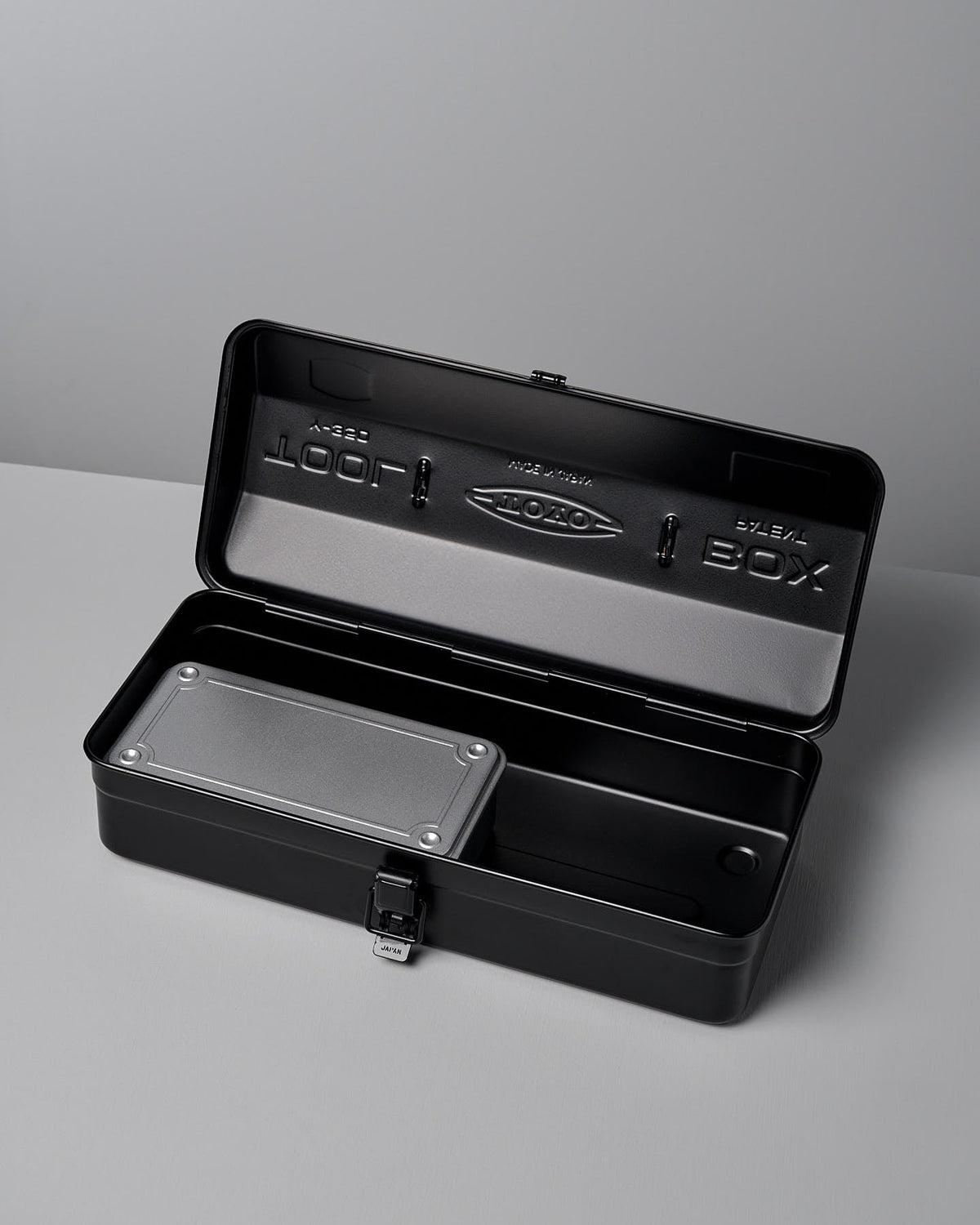 An open black metal toolbox with a latch, crafted from powder-coated steel, displays an empty two-compartment interior and a smaller removable tray inside the lid. Its sleek design has earned the TOYO STEEL Camber-Top Toolbox Y-350 – Black the prestigious Good Design Award.
