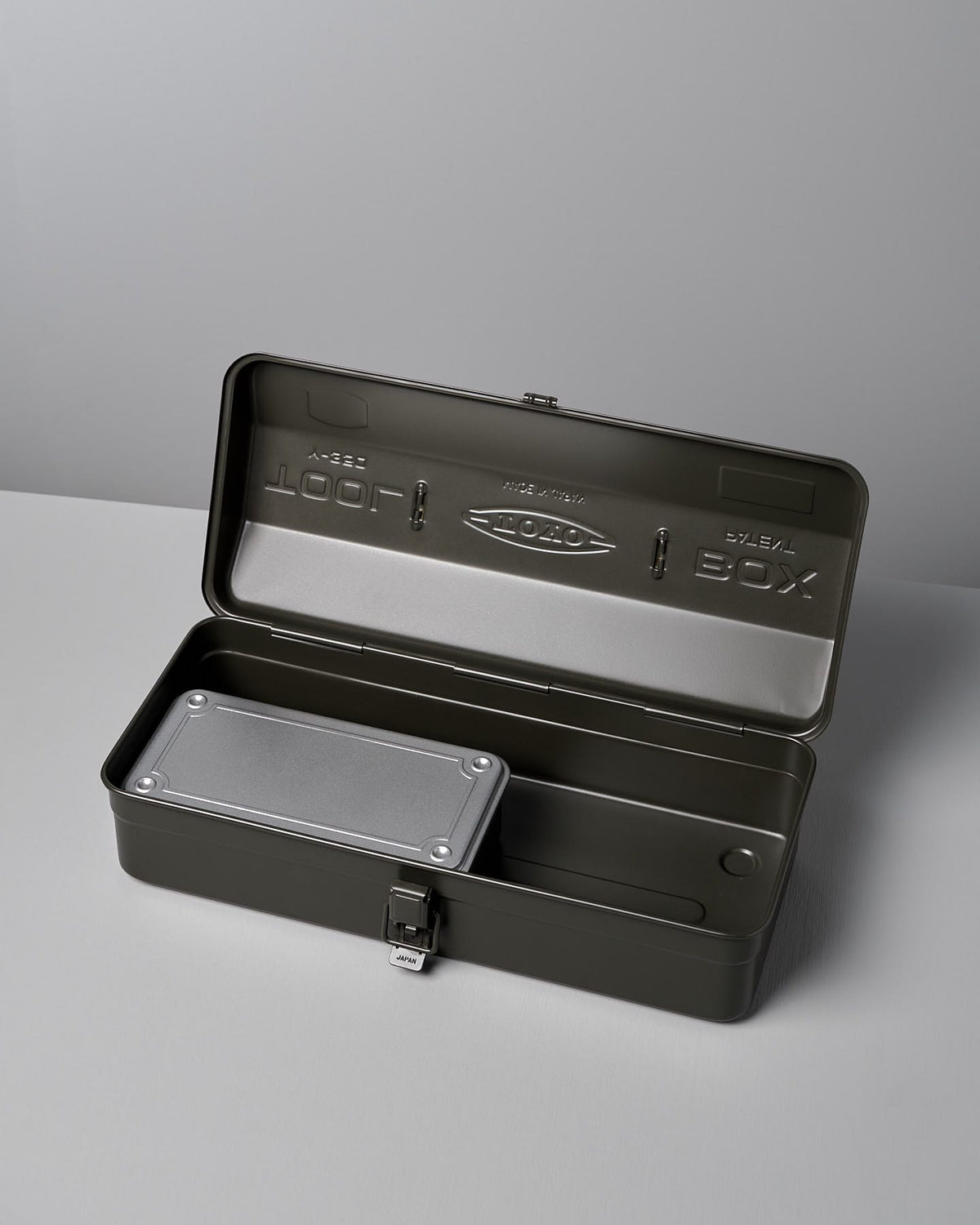 An open dark gray metal toolbox with a hinged lid, showcasing an inner tray and a built-in lock at the front. The Camber-Top Toolbox Y-350 – Moss Green by TOYO STEEL won the Good Design Award 2009, ensuring both durability and style in your workshop.