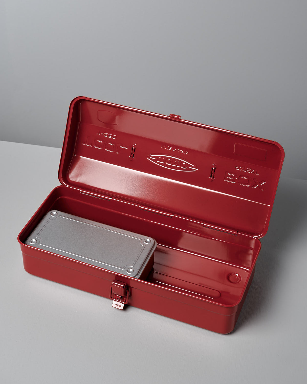Open Camber-Top Toolbox Y-350 – Red with a grey metal container inside, placed on a grey surface. This meticulously crafted toolbox by TOYO STEEL, boasts robust steel construction for lasting durability and style.