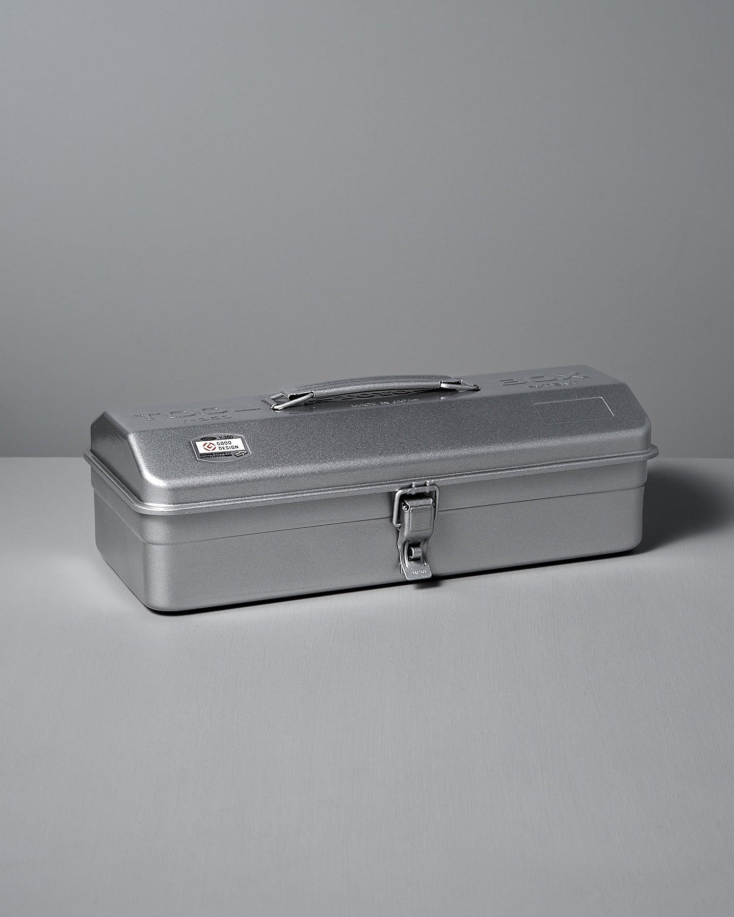 The TOYO STEEL Camber-Top Toolbox Y-350 in powder-coated silver elegantly rests on a gray surface, blending with the matching background.