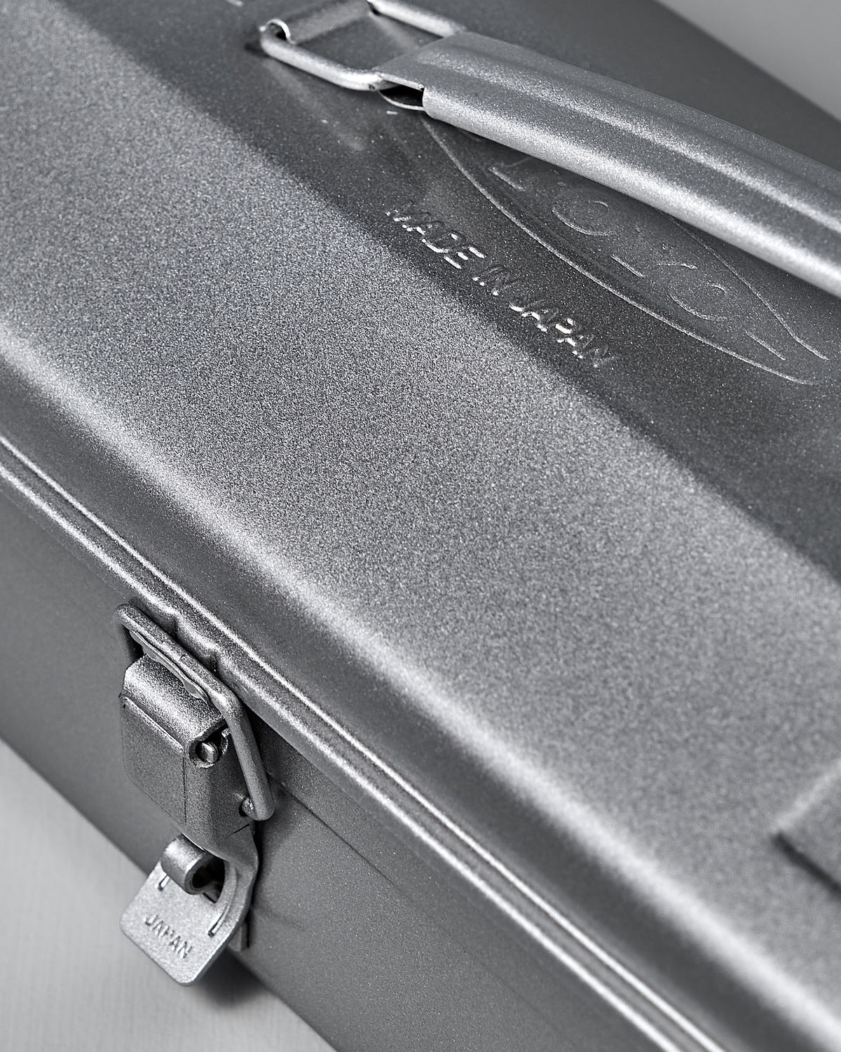 Close-up of the Camber-Top Toolbox Y-350 – Silver by TOYO STEEL, made from powder-coated steel with a latch and brand engraving on its lid. The cambered design adds elegance to its robust build, with a top handle for easy carrying.