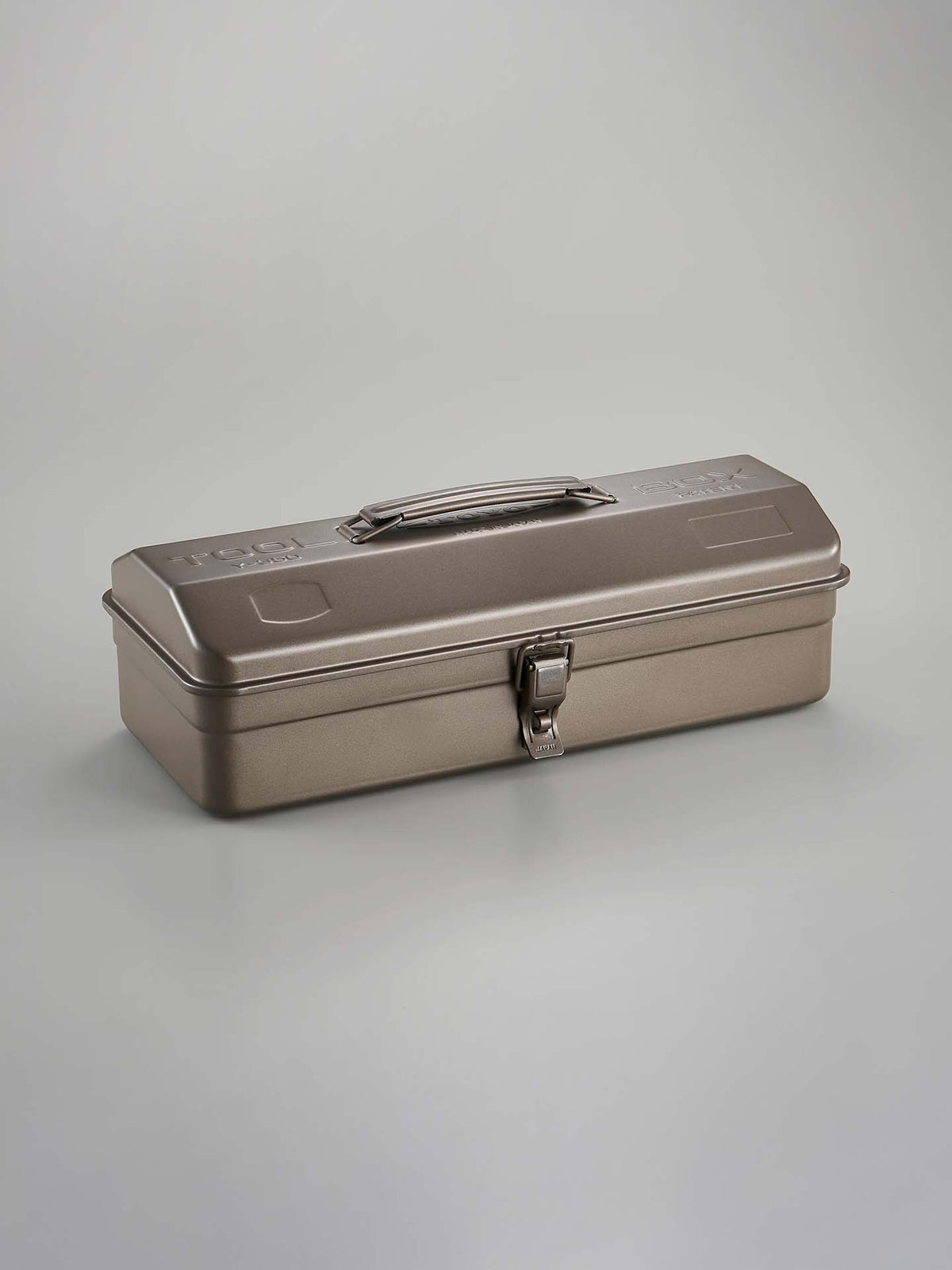 The Camber-Top Toolbox Y-350 – Titanium by TOYO STEEL, featuring a handle and latch, is acclaimed for its seamless aesthetic. Highlighted against a plain backdrop, this design earned the Good Design Award in 2009.