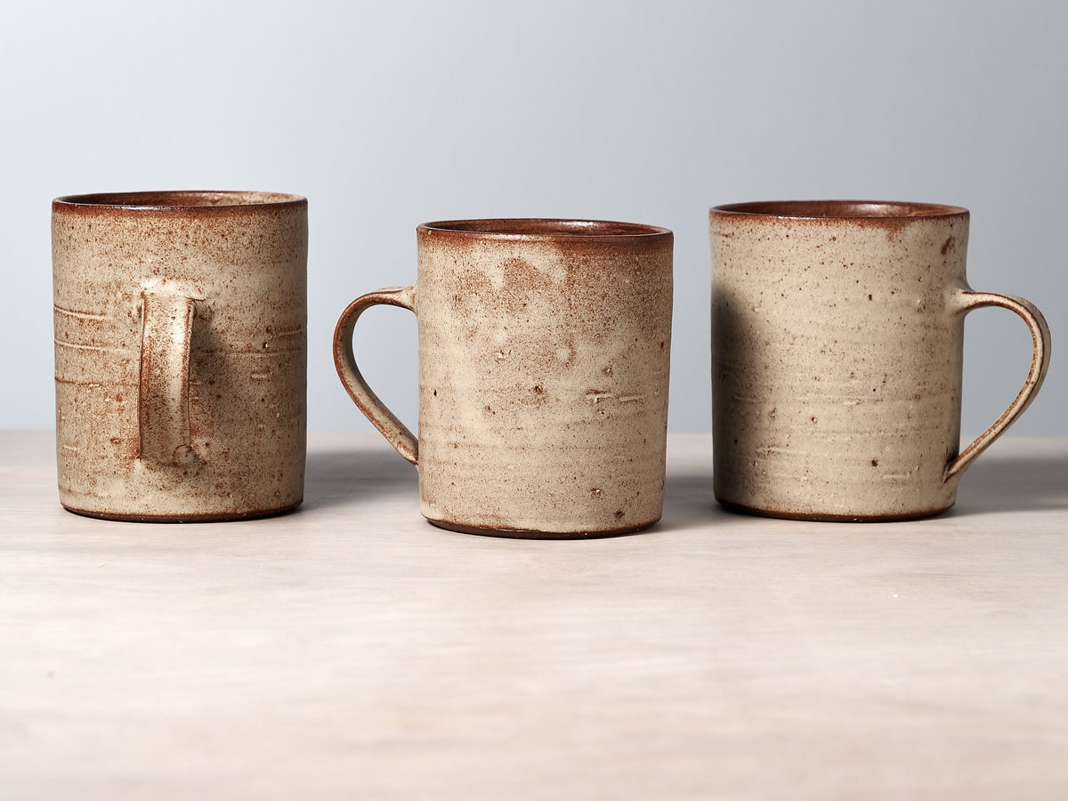 Three cream mugs with handles on a table.
