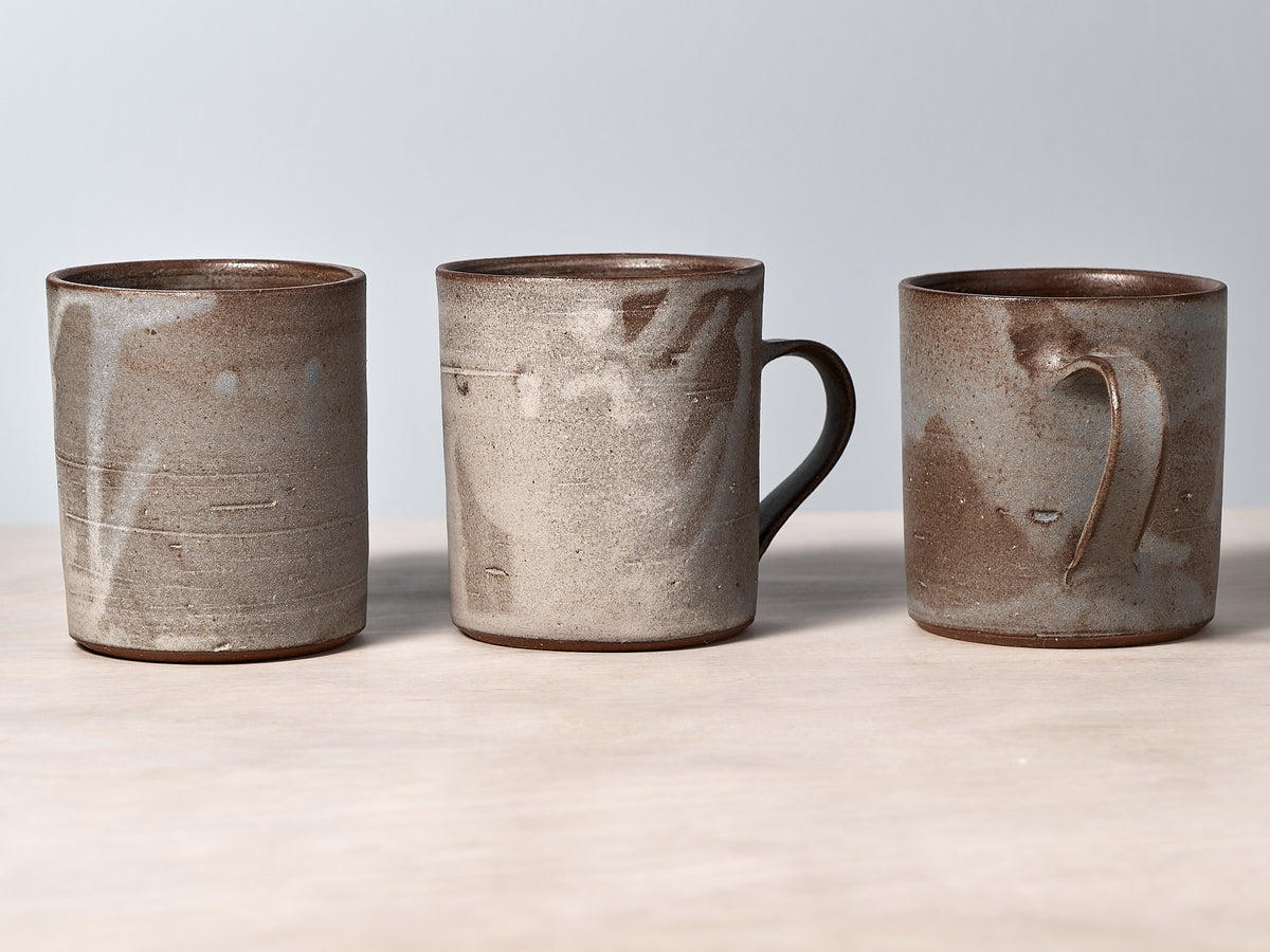 Three Zoë Isaacs grey-blue mugs sitting on top of a table.