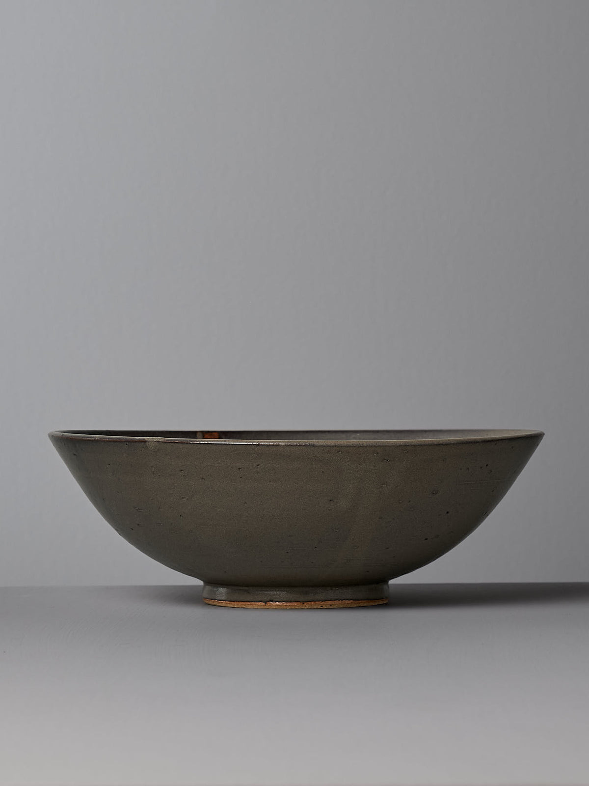 The Zoë Isaacs Serving Bowl – Dapple Brown is a round, shallow ceramic bowl featuring a matte, earthy brown glaze on a plain grey background. Crafted from toast-coloured clay and wheel-thrown, this bowl showcases the fine artistry of handmade products.