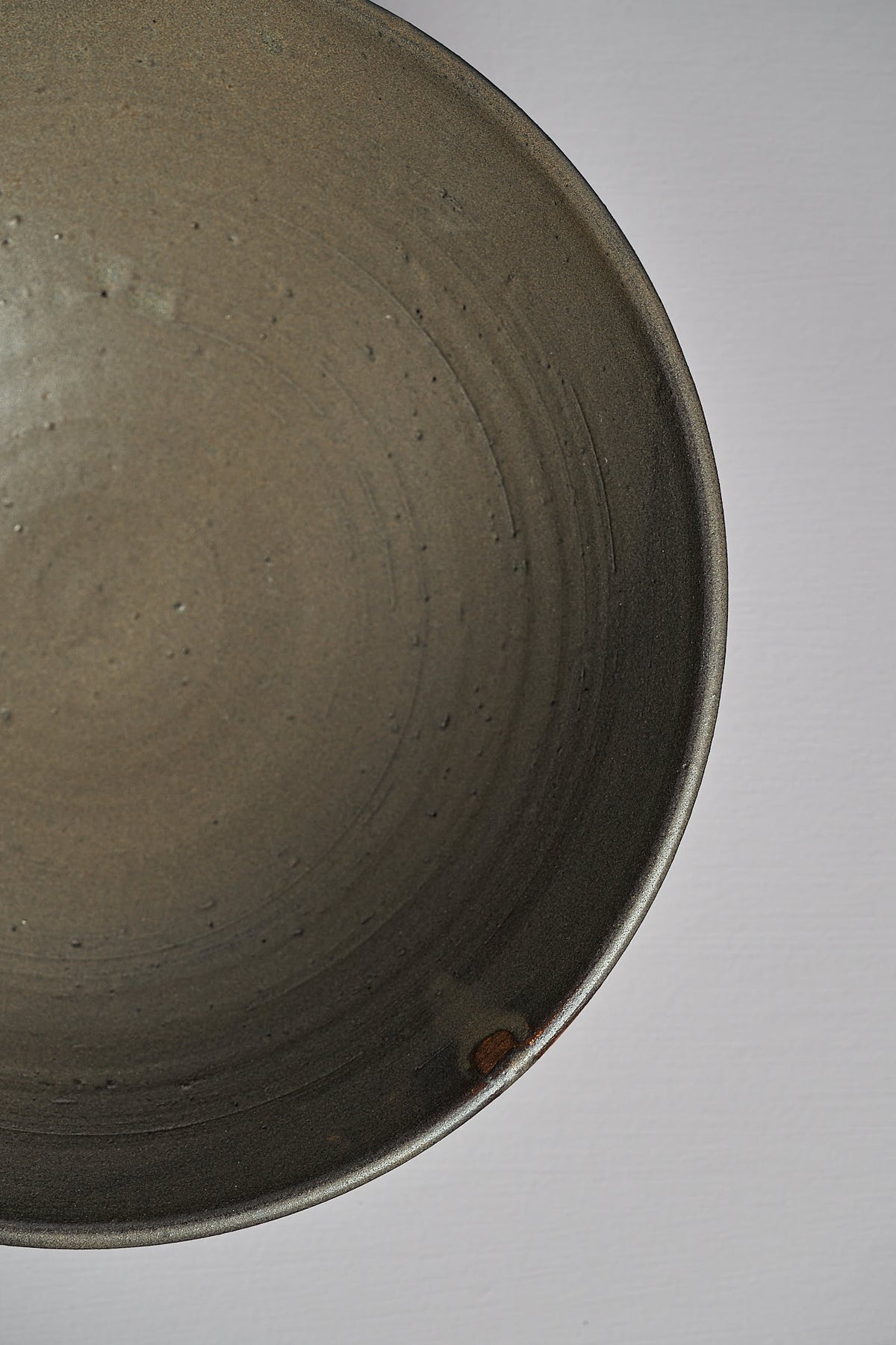 Close-up view of the interior of a textured, dark Serving Bowl – Dapple Brown made from toast-coloured clay by Zoë Isaacs against a white background.