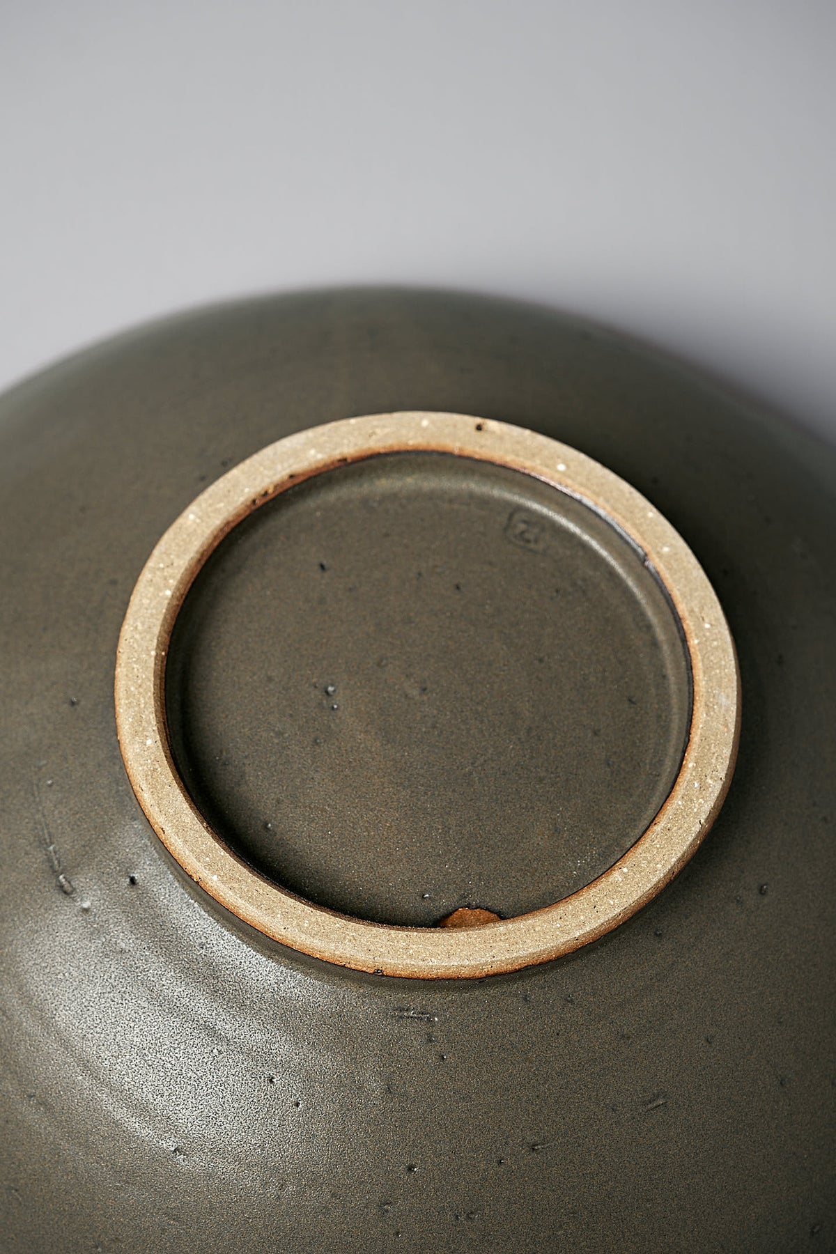 Close-up view of the base of a Zoë Isaacs Serving Bowl – Dapple Brown, showing its unglazed foot ring against a light gray background.