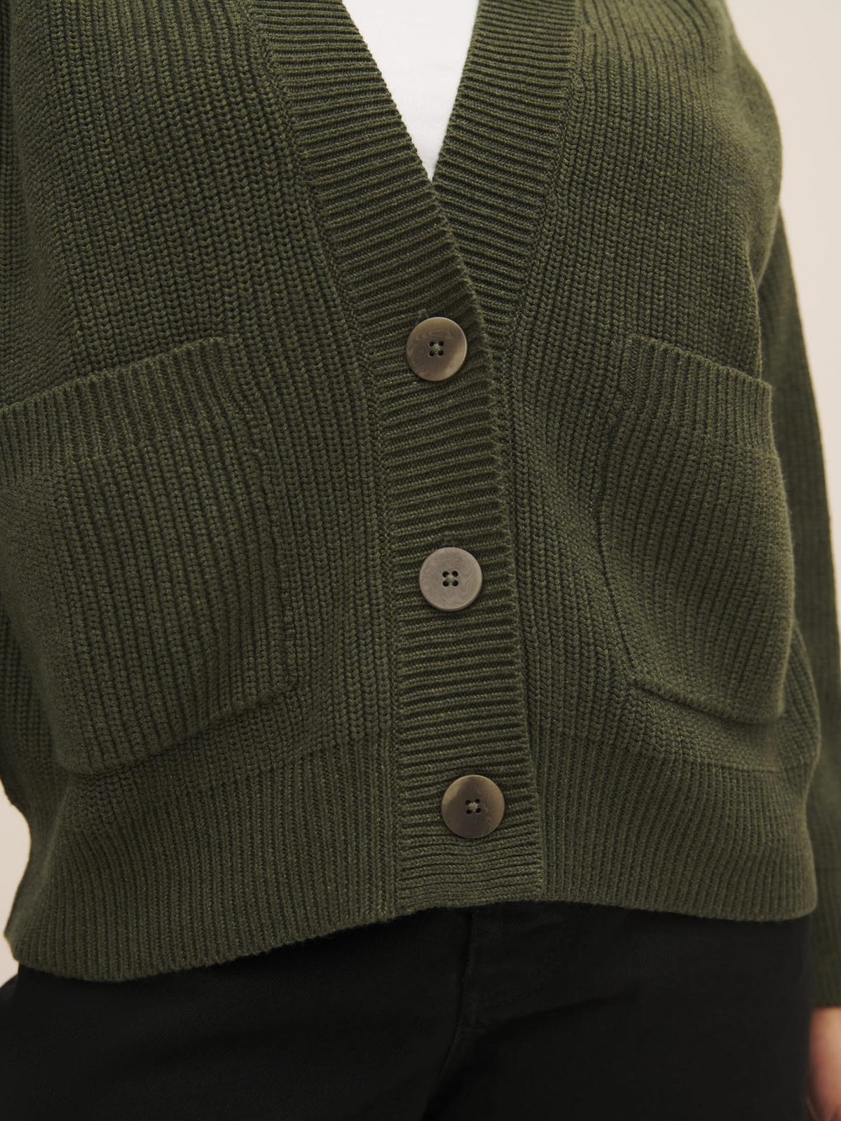 Close-up of a green Hannes Cardigan – Khaki Marle with three brown buttons by Kowtow.