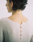 A person with short, dark hair seen from behind wears the Form Top – Ivory, a petite ribbed style in a light color with cutout and button details on the upper back.