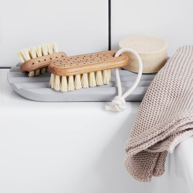 A Iris Hantverk concrete tray and a towel on a bathroom shelf.