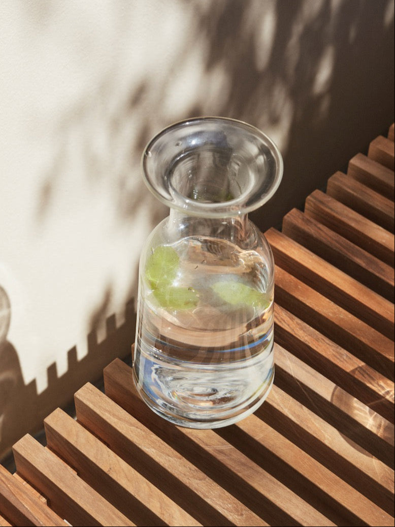 A Skagerak Hammer Decanter sits on a wooden bench.