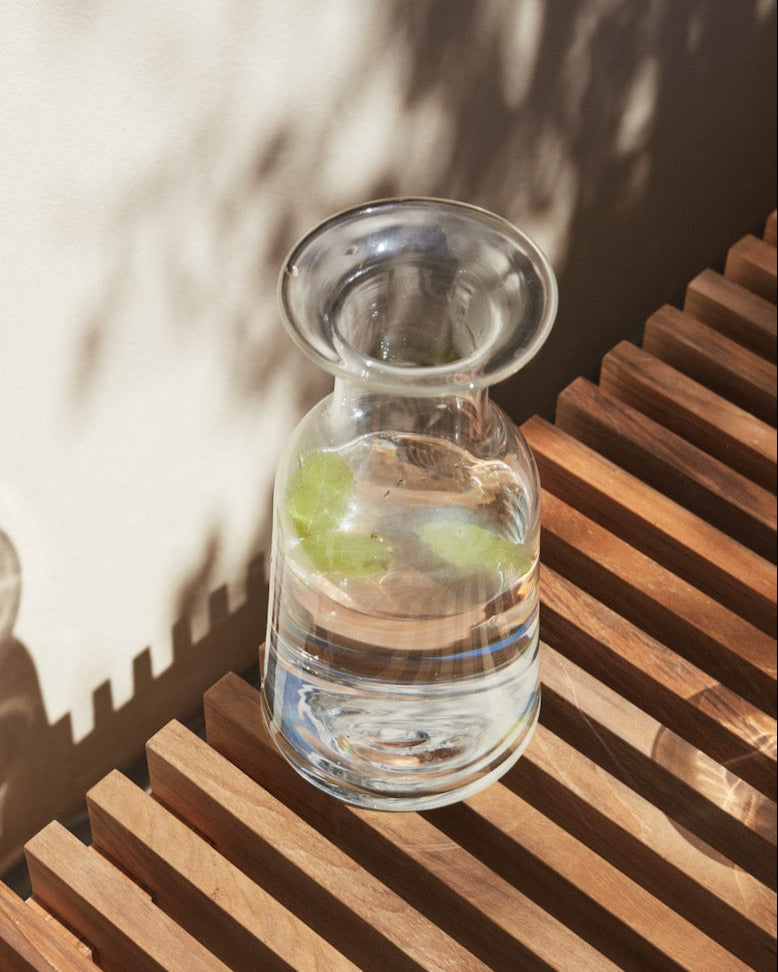 A Skagerak Hammer Decanter sits on a wooden bench.
