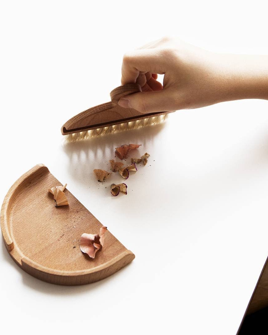 An Iris Hantverk Nesting Table Brush & Pan Set with bristles on a gray surface.