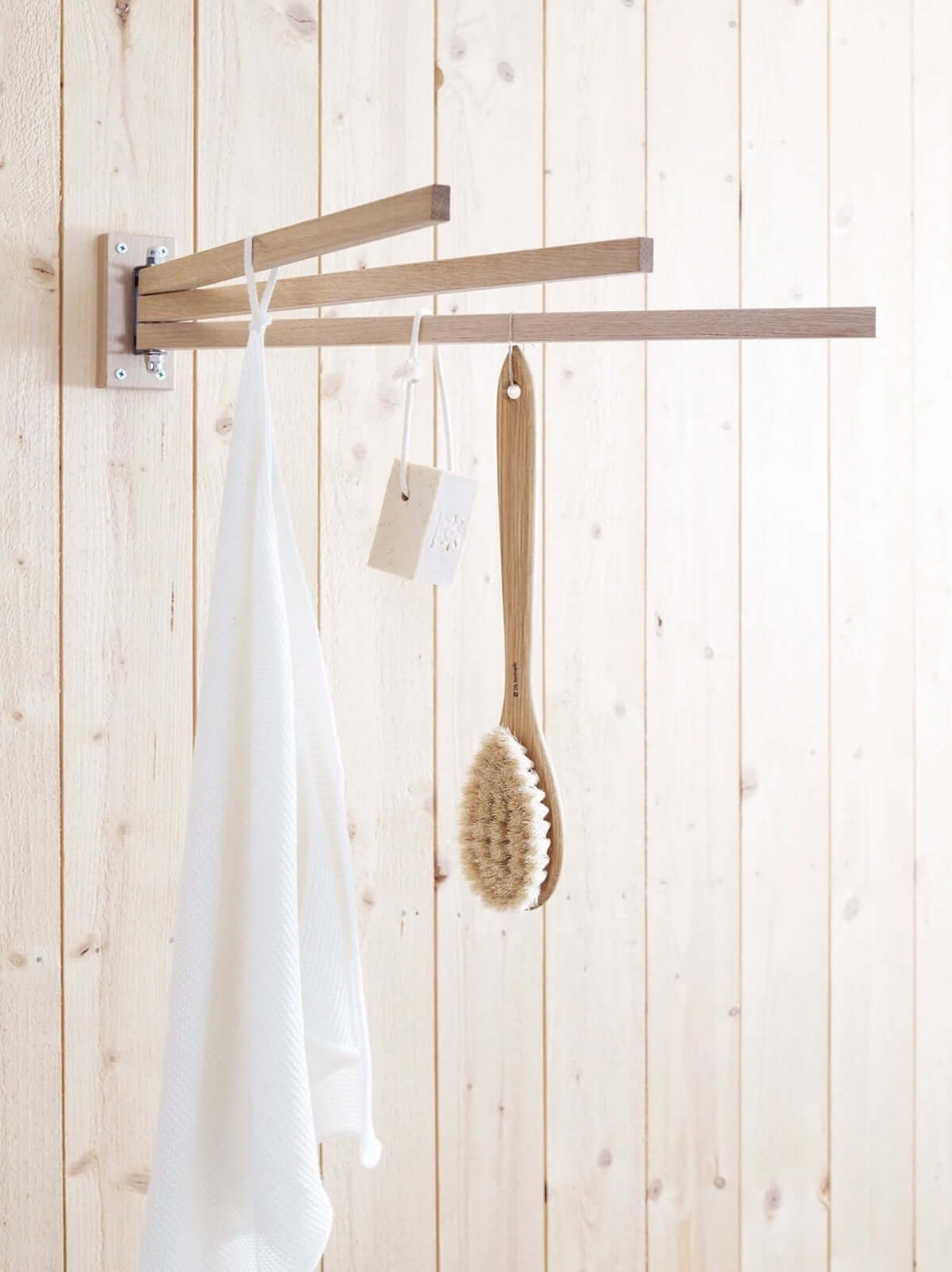 A wooden drying rack with towels and brushes hanging on it.