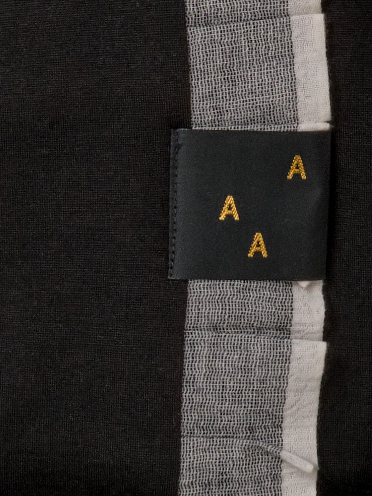 A black Baby Merino Blanket - Black/Ice Blue AAA Design tag with yellow letters on it.