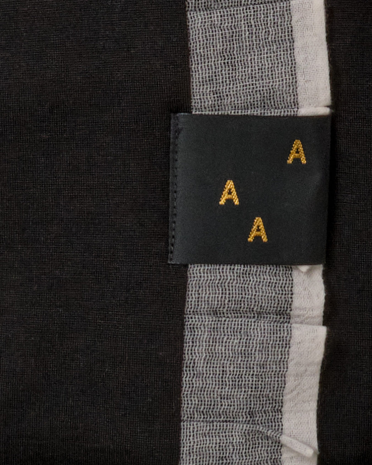 A black Baby Merino Blanket - Black/Ice Blue AAA Design tag with yellow letters on it.