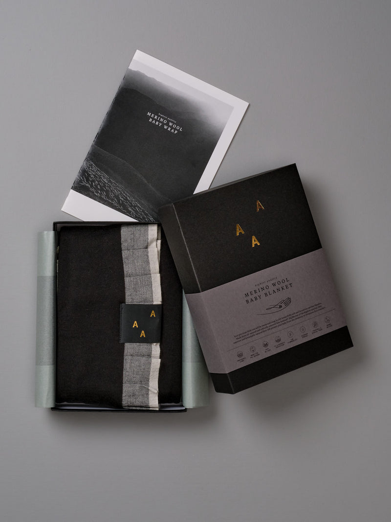 A box with a AAA Design baby merino blanket - Black/Ice Blue and a picture.
