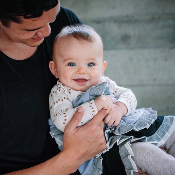 A man holding a baby wrapped in a cozy AAA Design Baby Merino Blanket - Black/Ice Blue.