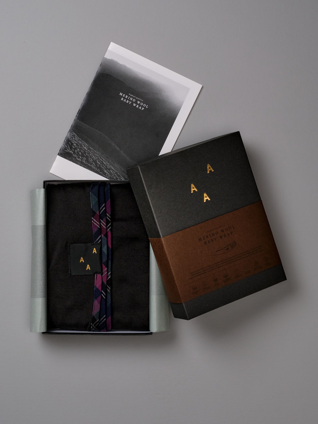 A Baby Merino Wrap - Black gift box with a card inside by AAA Design.