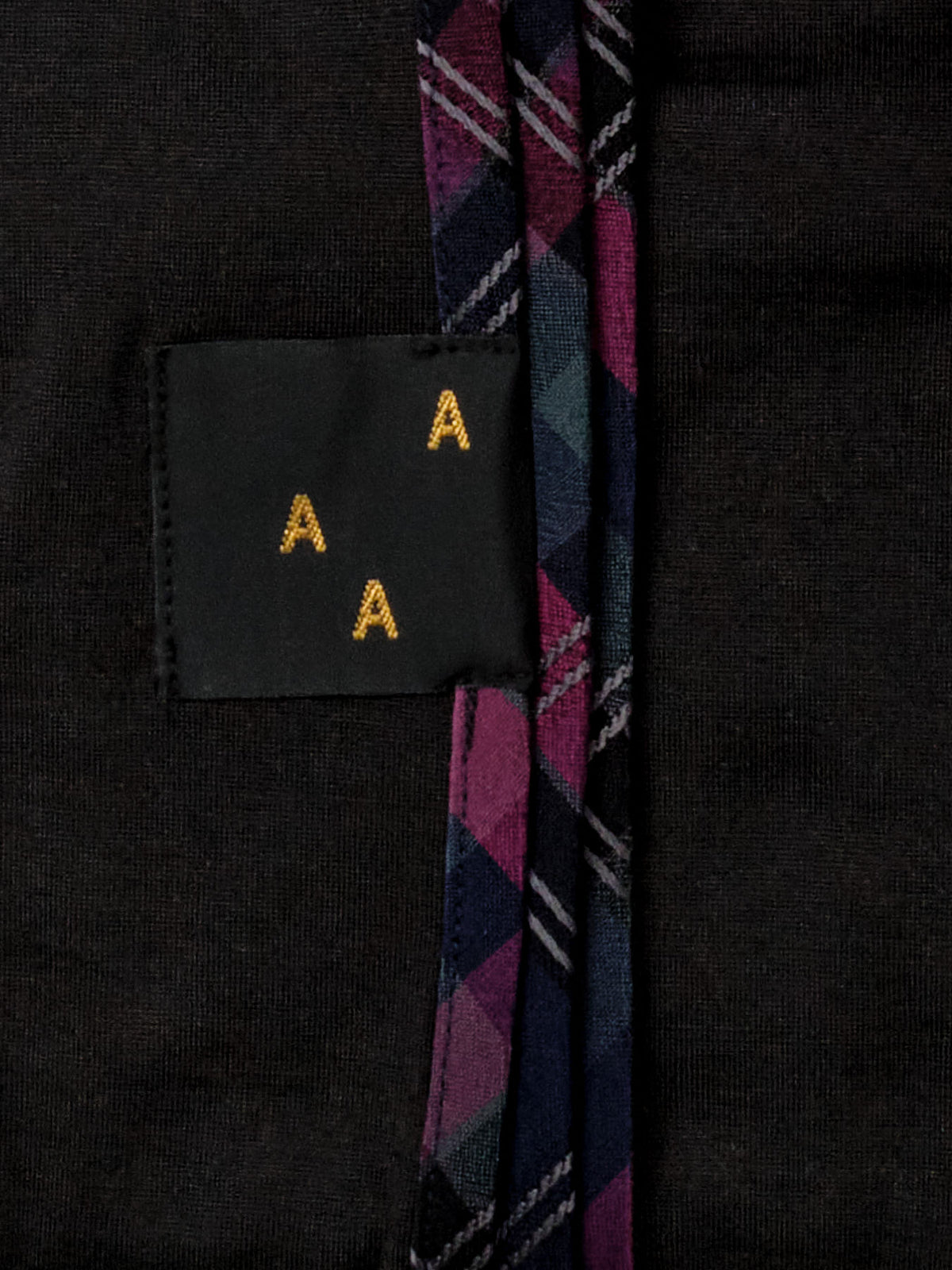 A black and purple plaid tie with an AAA Design on it.