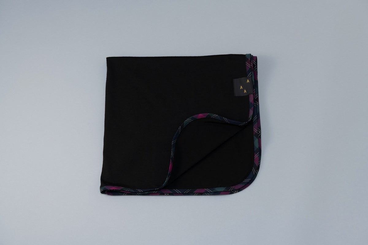 An AAA Design Baby Merino Wrap – Black with a colorful pattern on it.