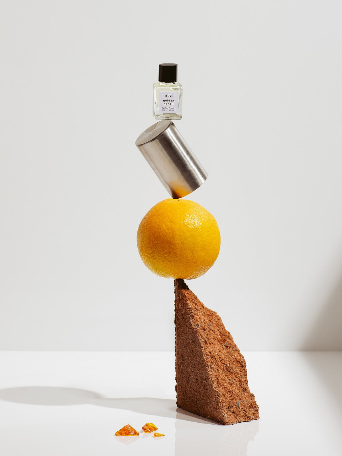 A bottle of Golden Neroli Parfum Extrait – for balance by Abel on top of an orange.