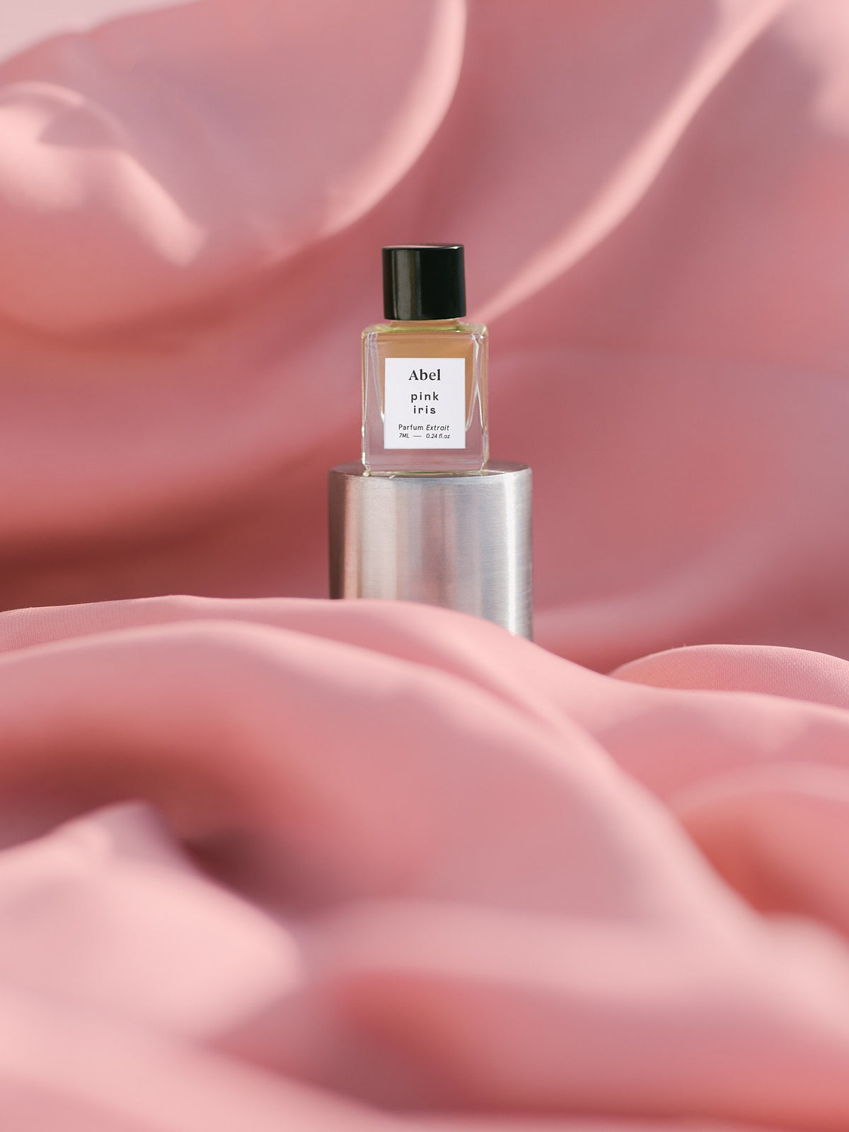A highly concentrated bottle of the Abel Pink Iris Parfum Extrait – for calm sitting on top of a pink fabric.