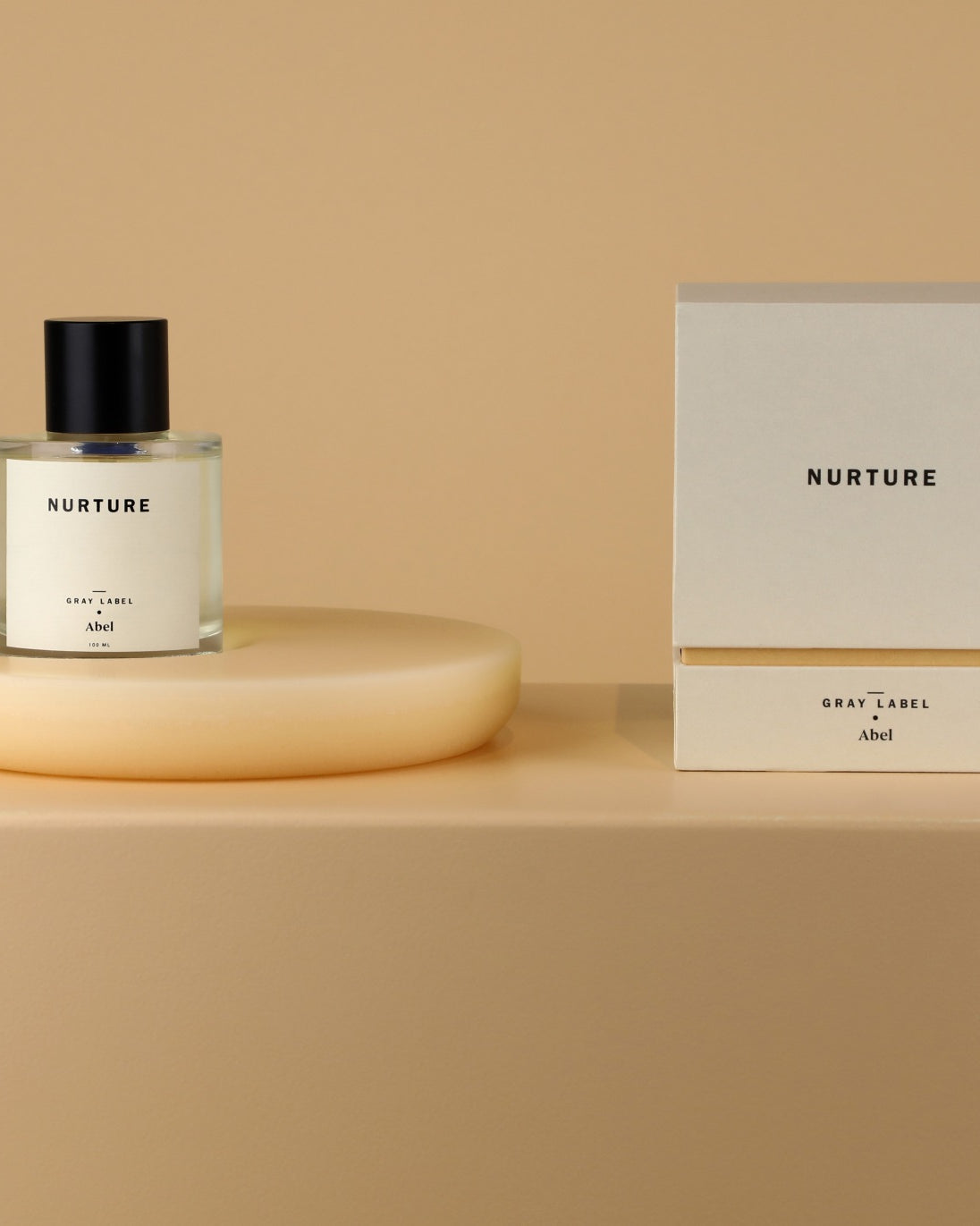 An NURTURE - grey label fragrance bottle sits on a table next to a plant by Abel.