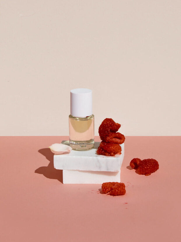 A bottle of Pink Iris – a contemporary, classic floral eau de parfum by Abel sitting on a pink surface.