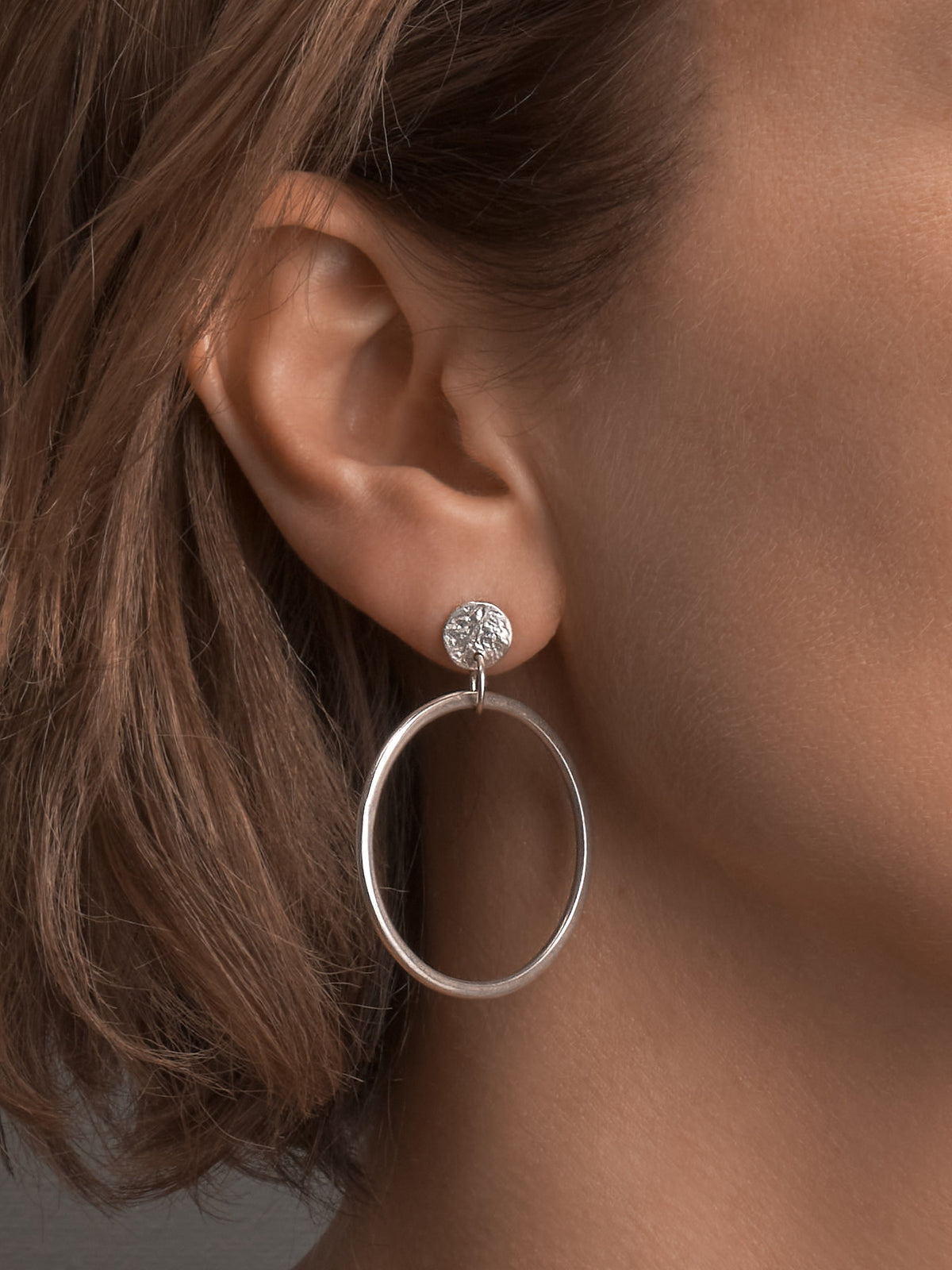 A woman wearing a pair of Ripple Loop Earrings from Amy Iddles Jeweller.