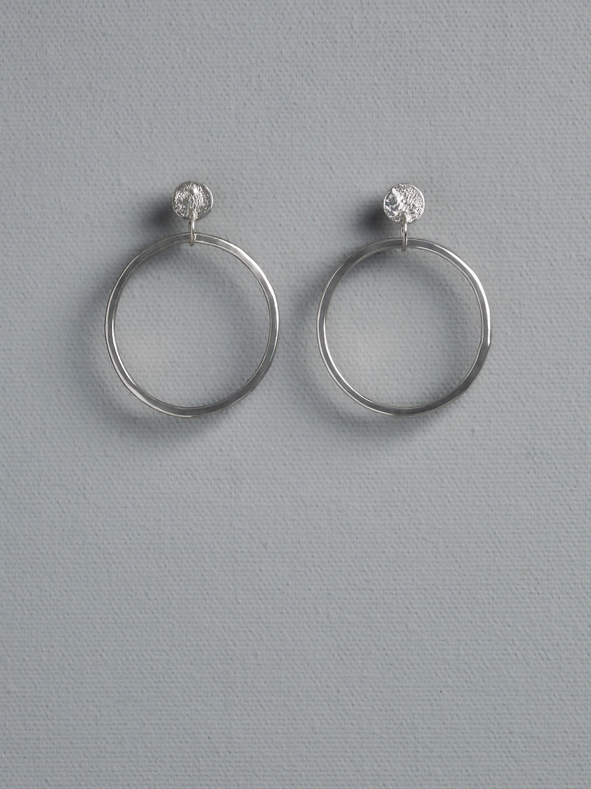 A pair of Ripple Loop Earrings by Amy Iddles Jeweller with a diamond in the middle.