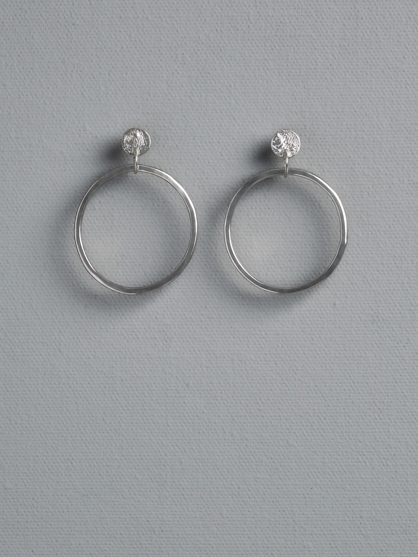 A pair of Ripple Loop Earrings by Amy Iddles Jeweller with a diamond in the middle.