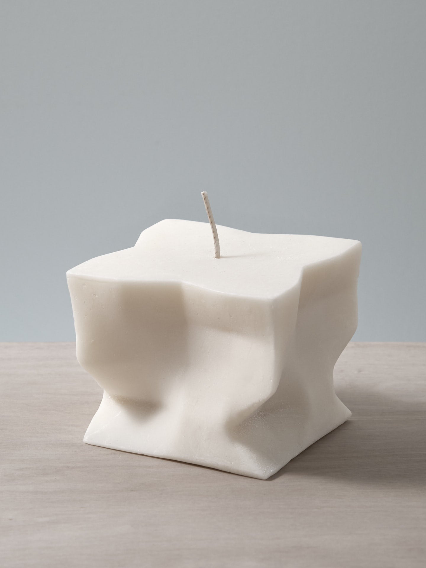 A Baltazar Candle sitting on top of a wooden table. (Brand Name: Andrej Urem)
