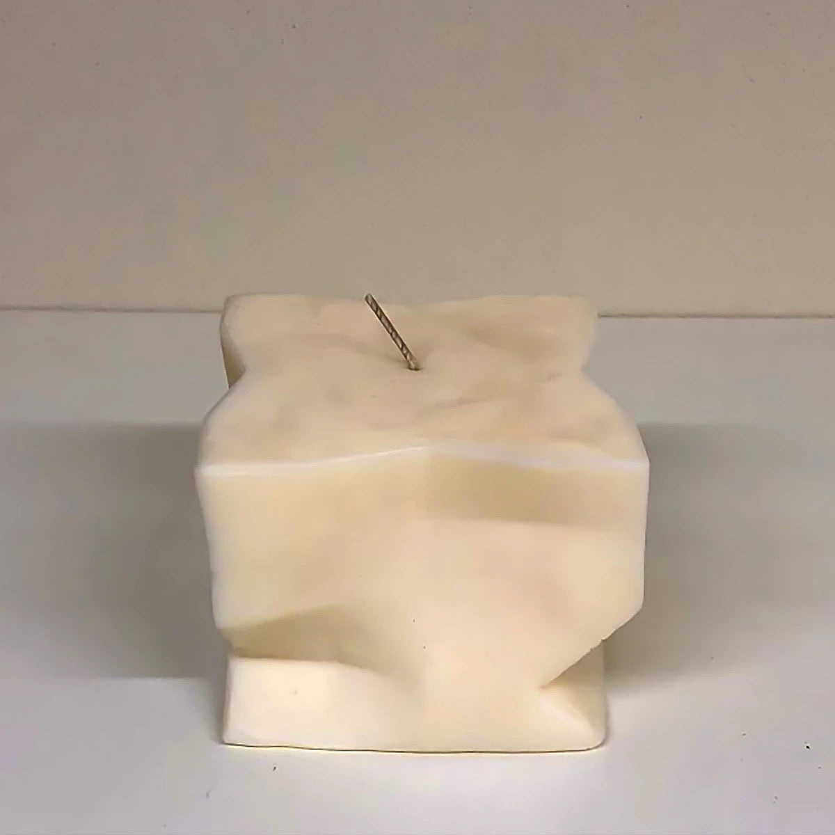 A Baltazar Candle by Andrej Urem sitting on top of a white surface.