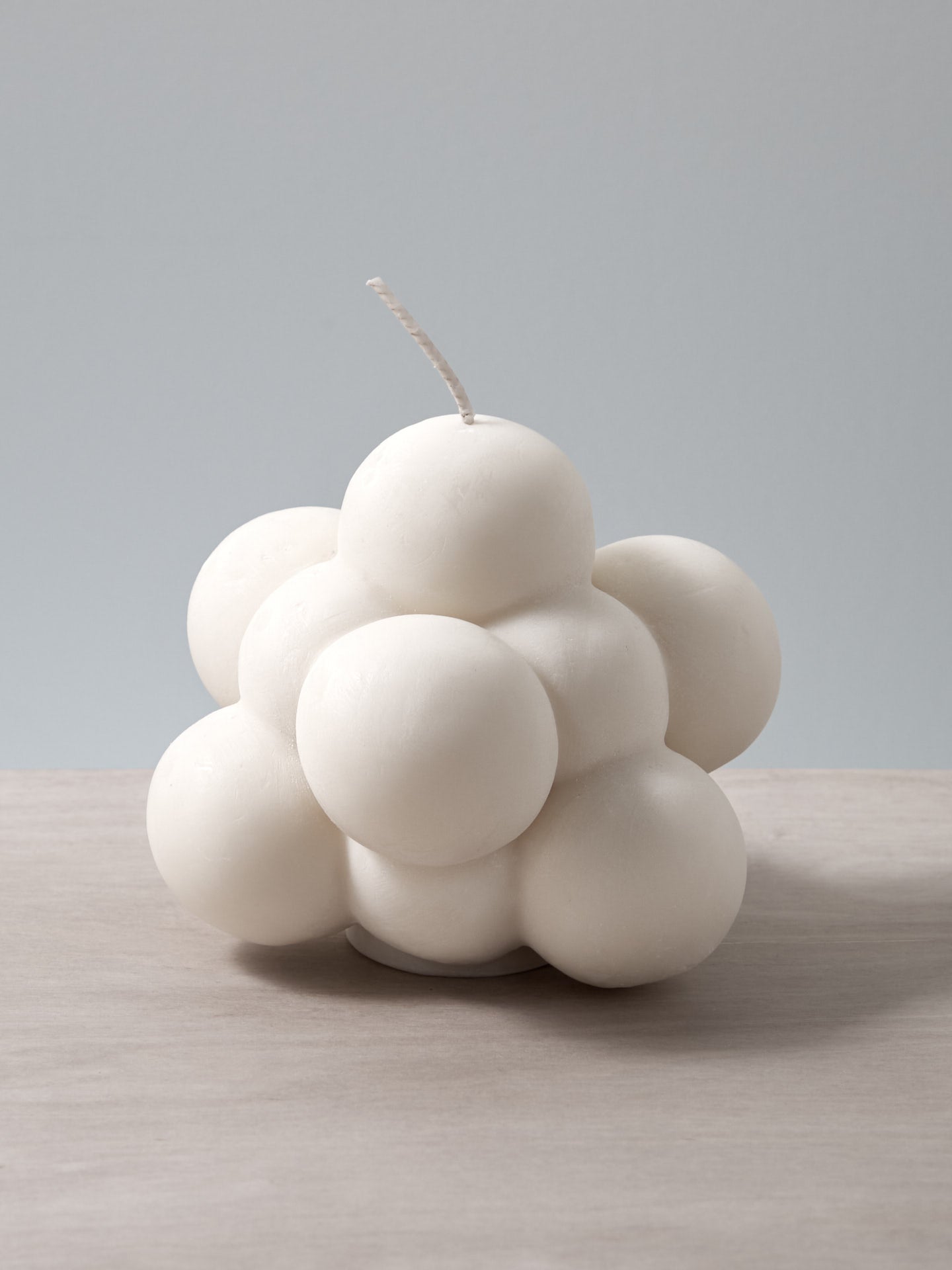 An Andrej Urem Molecule Candle shaped like a cloud sitting on a table.