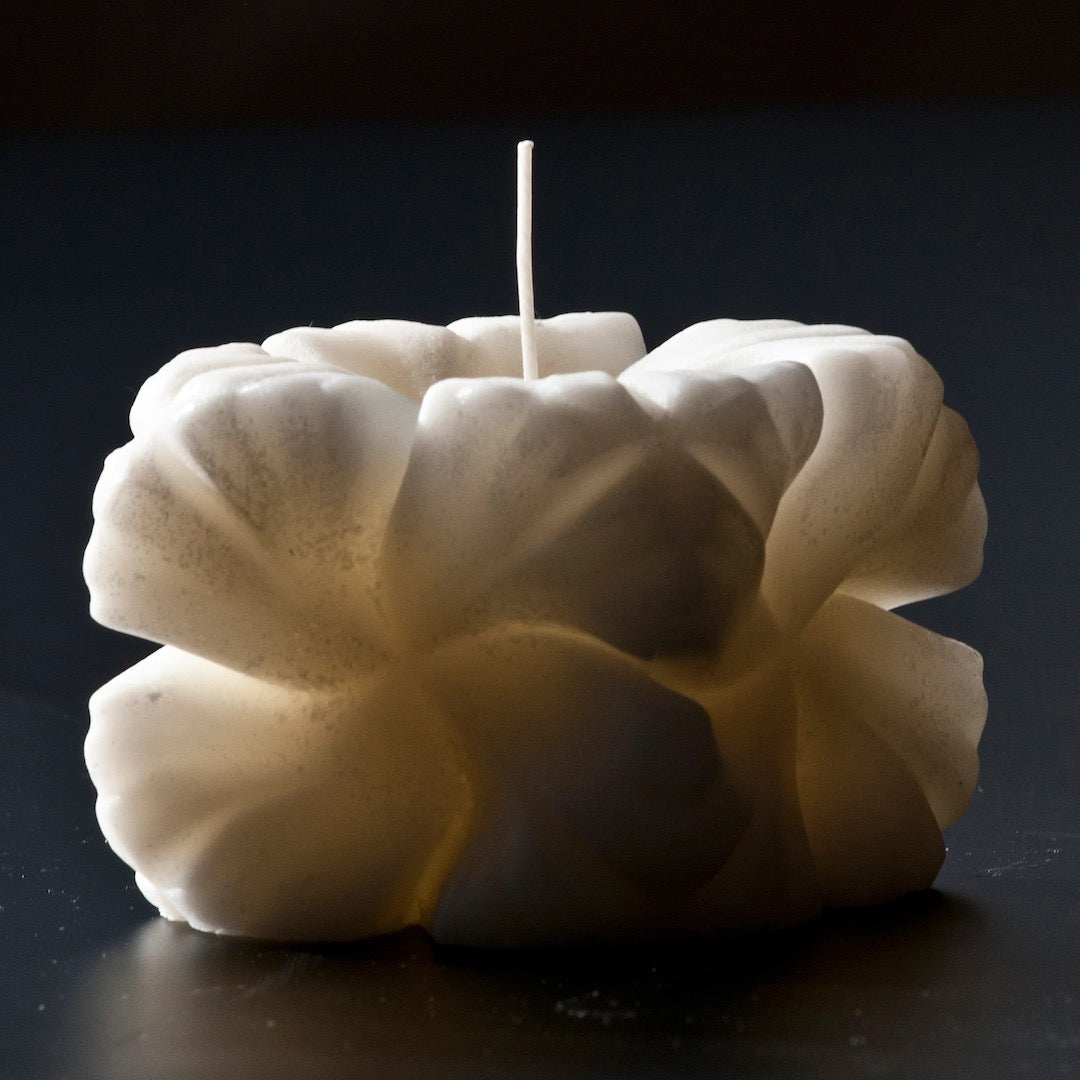 An Andrej Urem Rose candle sitting on a black surface.