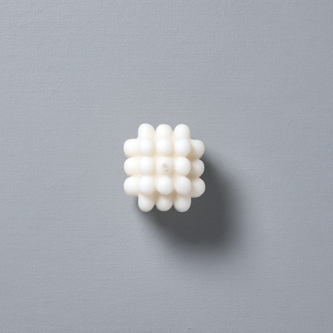 An Andrej Urem Milk Candle – mini, a white object with many small dots.