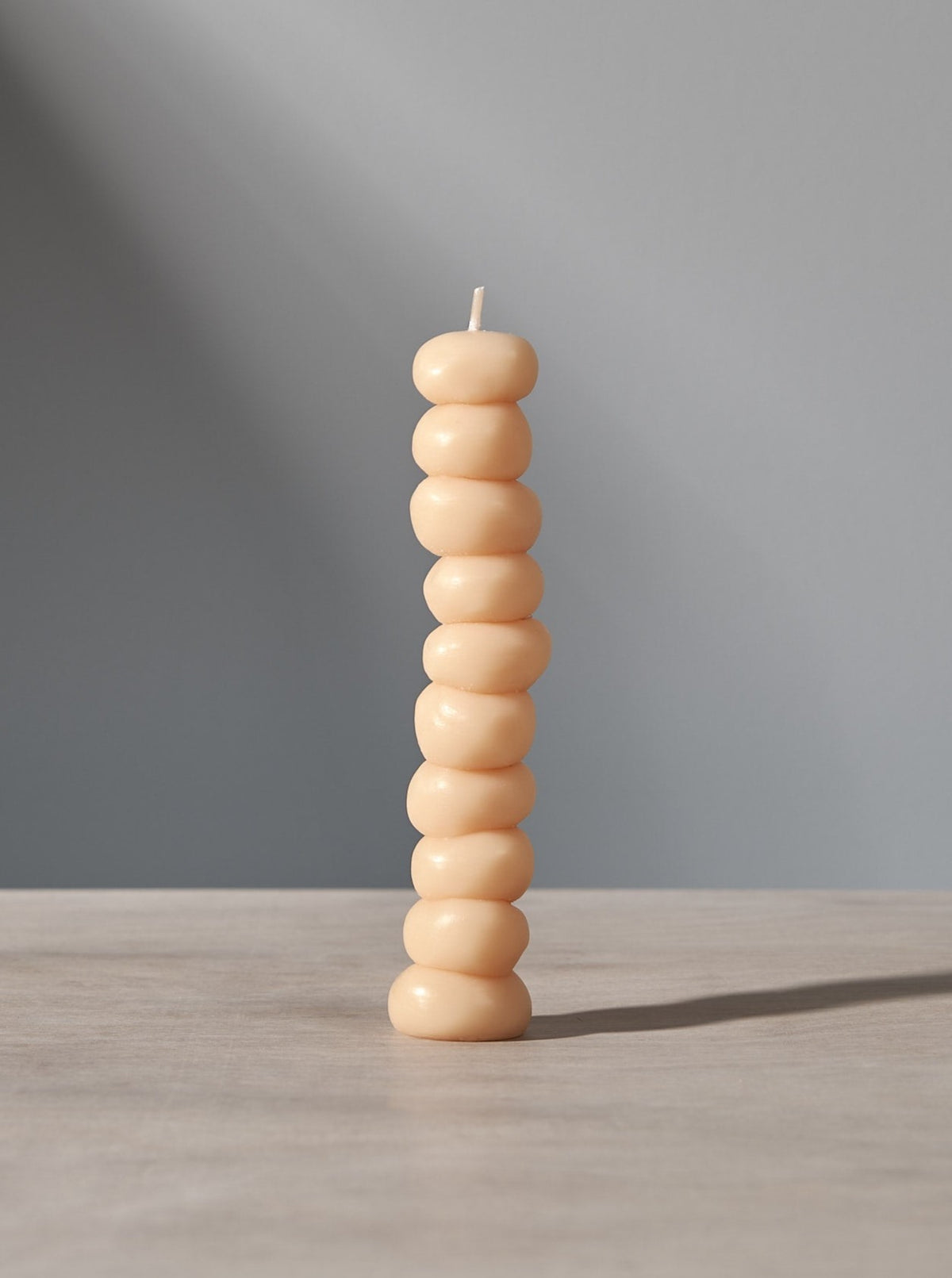 A stack of Grape Candles by ann vincent on a table with a light behind them.