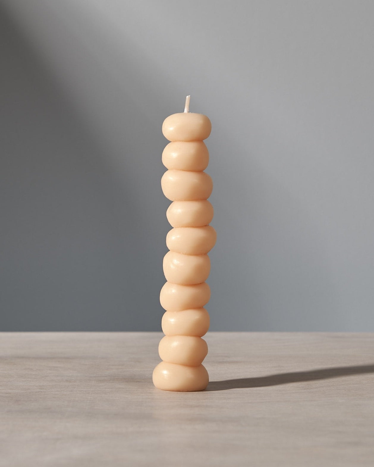 A stack of Grape Candles by ann vincent on a table with a light behind them.