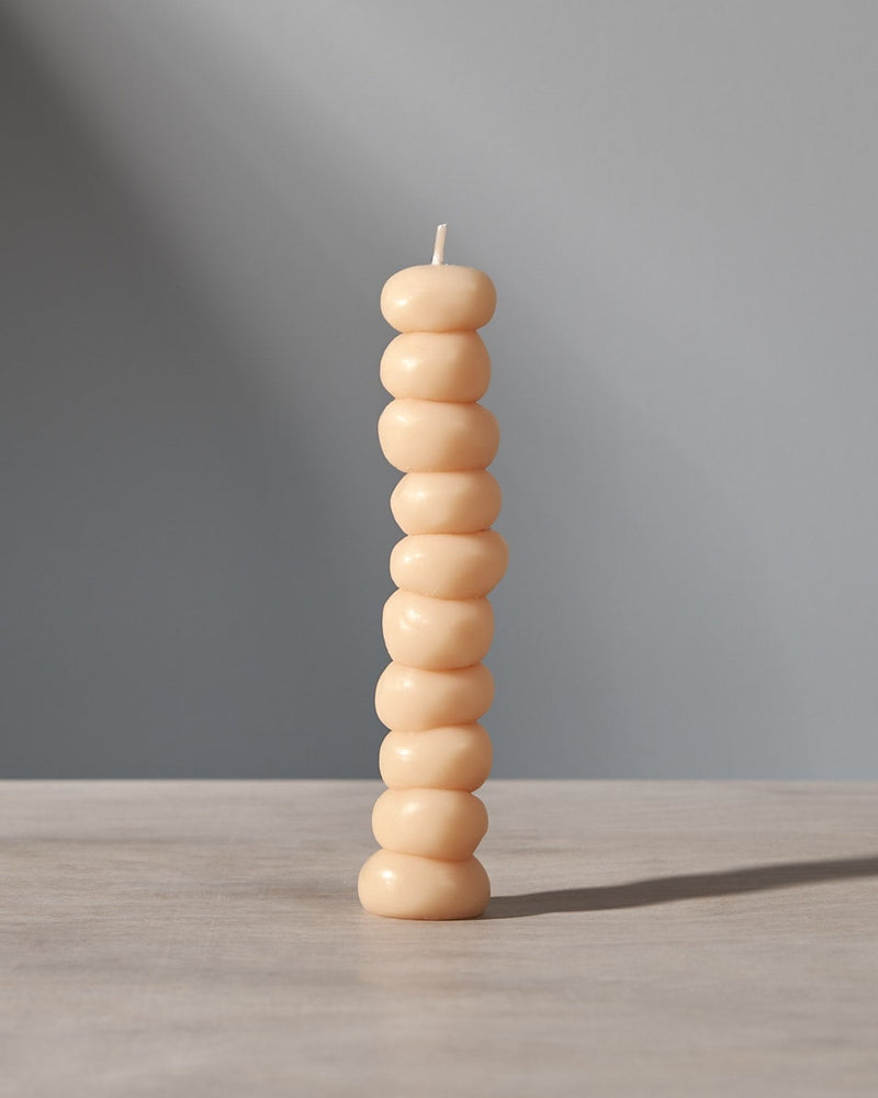A stack of Grape Candles by ann vincent on a table with a light behind them.