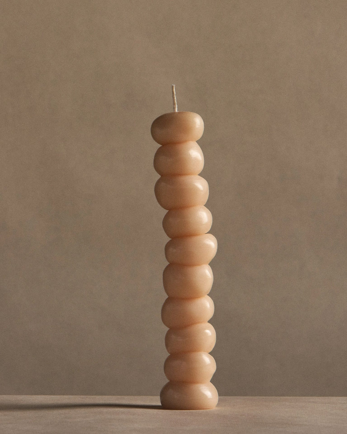 A stack of ann vincent Grape Candles on a table with a beige background.