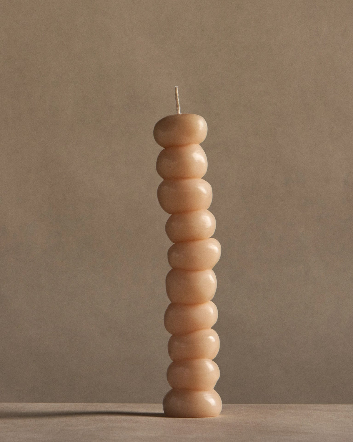 A stack of ann vincent Grape Candles on a table with a beige background.