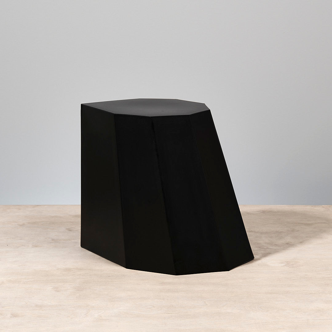 A Arnoldino Stool – Black by Martino Gamper, sitting on top of a wooden table.