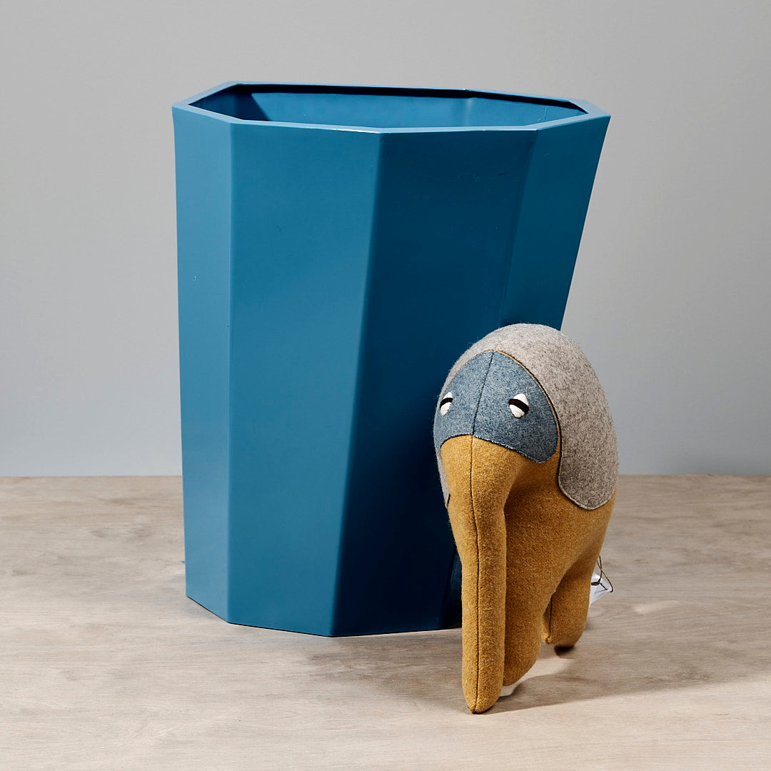 A Martino Gamper Arnold Circus Stool – Boat Blue sits next to a blue trash can.