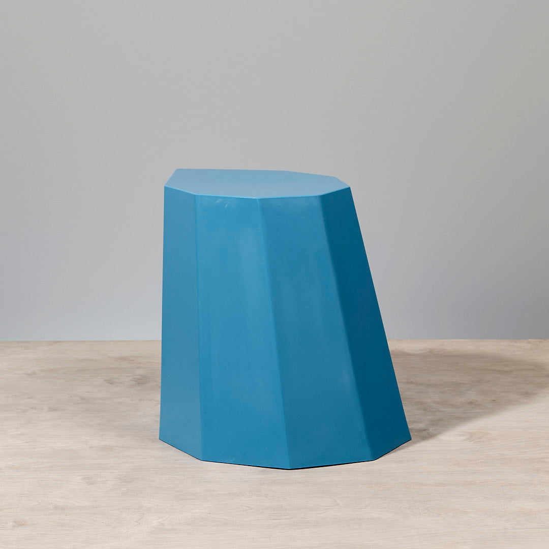 An Arnoldino Stool – Boat Blue by Martino Gamper sitting on top of a wooden table.