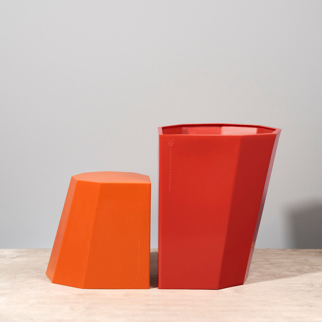 An Arnoldino Stool - Red by Martino Gamper sitting on a wooden table.