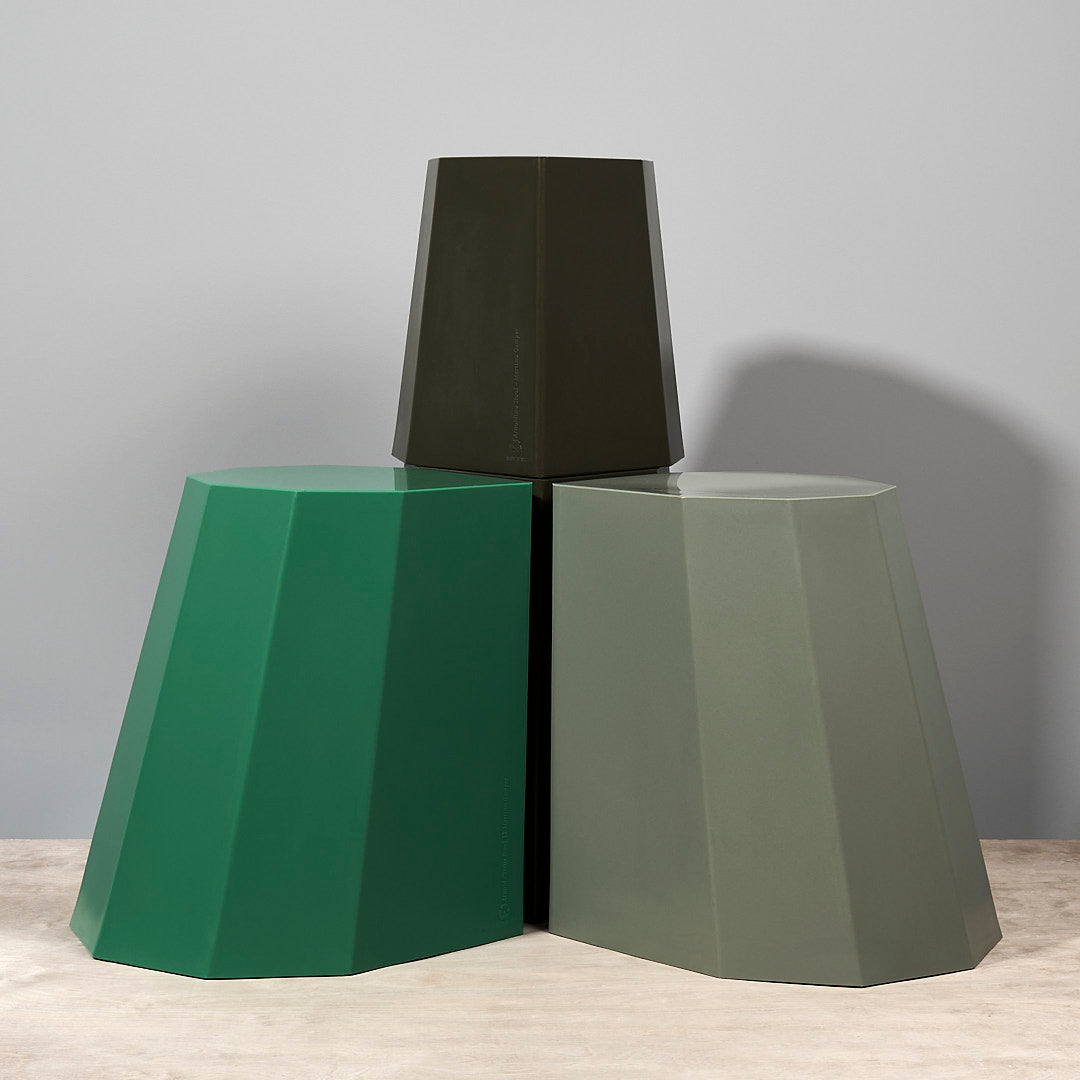 Three Arnold Circus Stools – Khaki by Martino Gamper on top of a wooden table.