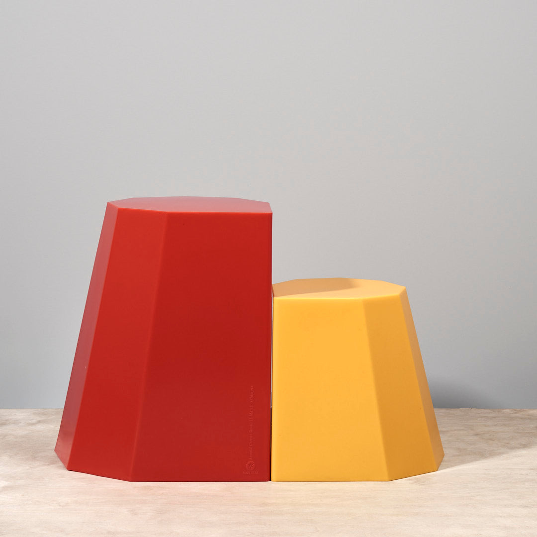 Two Arnoldino Stools - Red by Martino Gamper on a table.