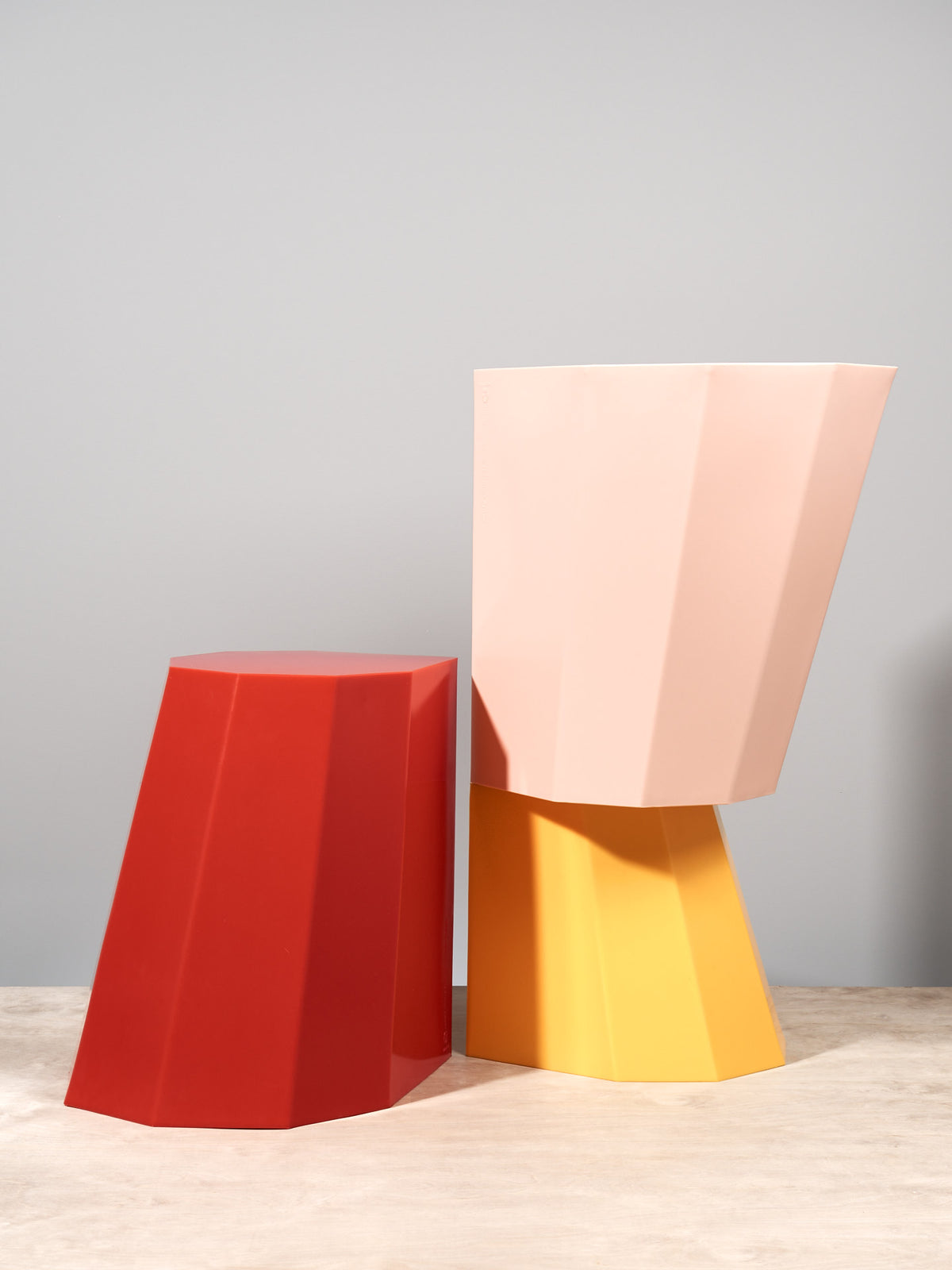 A pair of colorful Arnoldino Stools – Red by Martino Gamper on a wooden table.